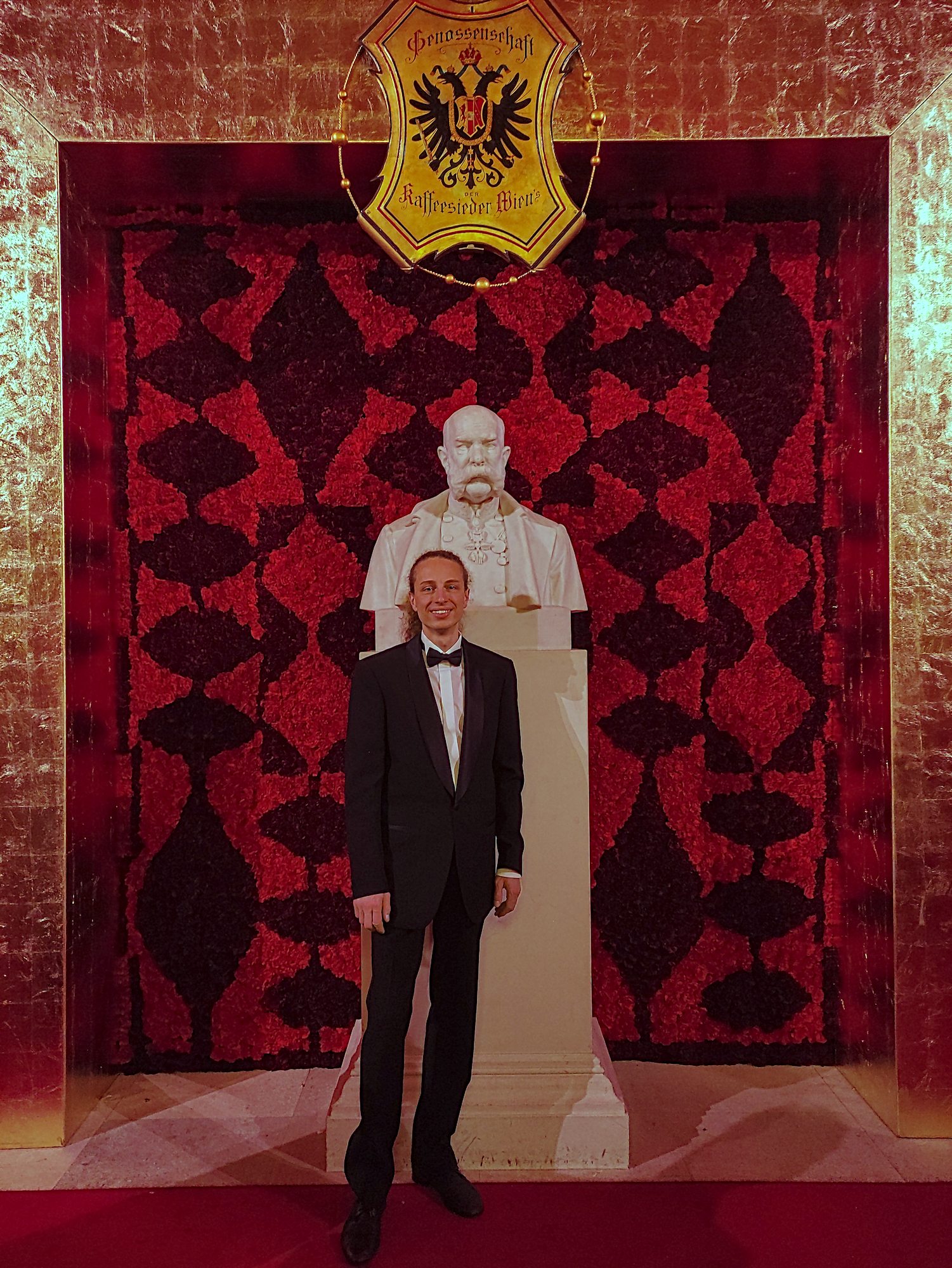 Harald steht im Anzug vor einer weißen Statue in der Hofburg (Kaffeesiederball 2026)