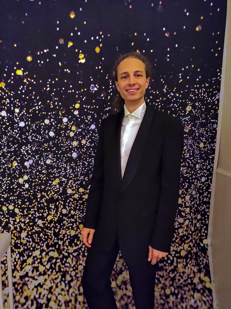 Harald steht im Anzug vor einem blauen Hintergrund (Ball in den Sofiensälen 2025)